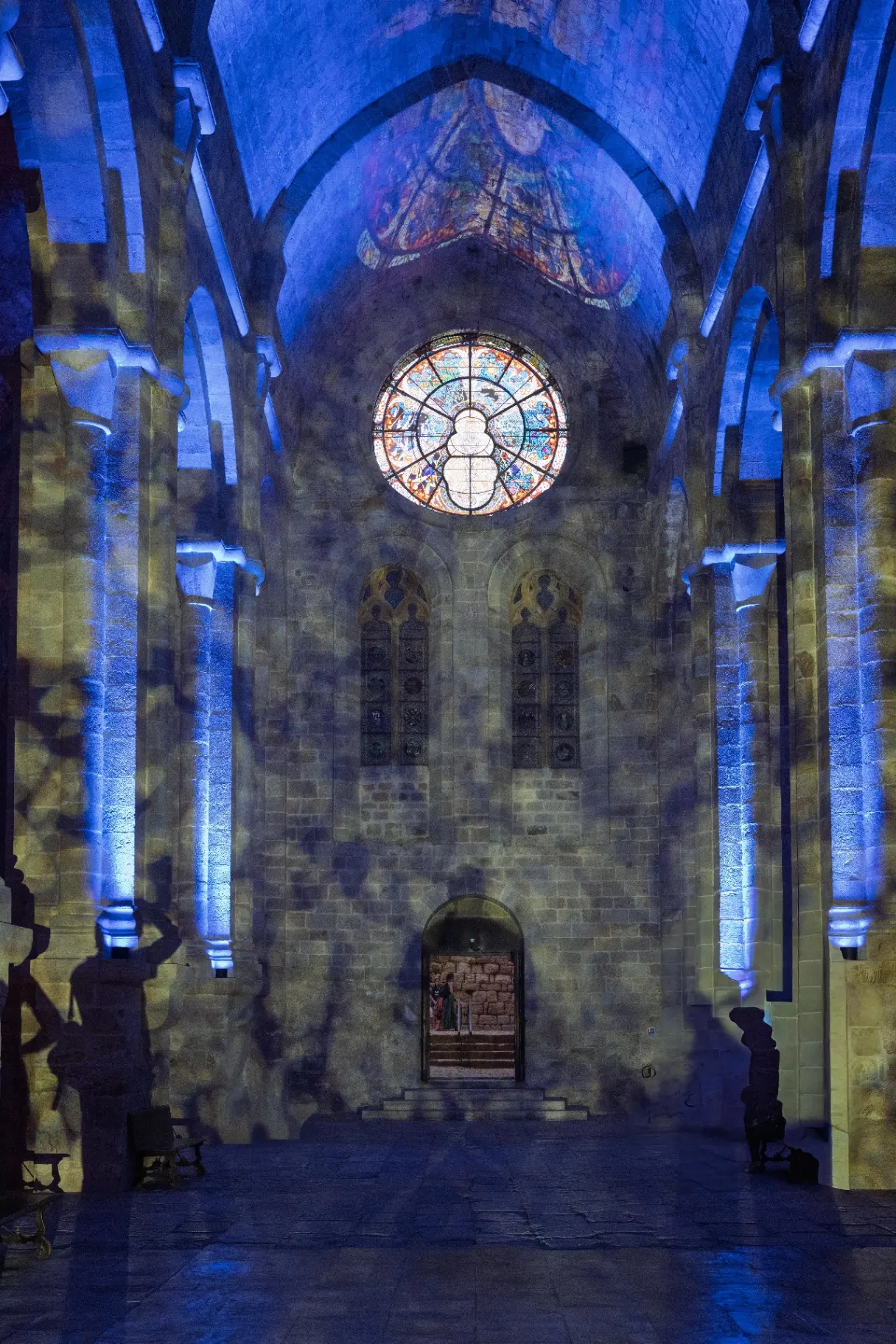 Rose window and stained glass of the nave with light patterns projected onto the vaults and walls, Fontfroide Abbey.