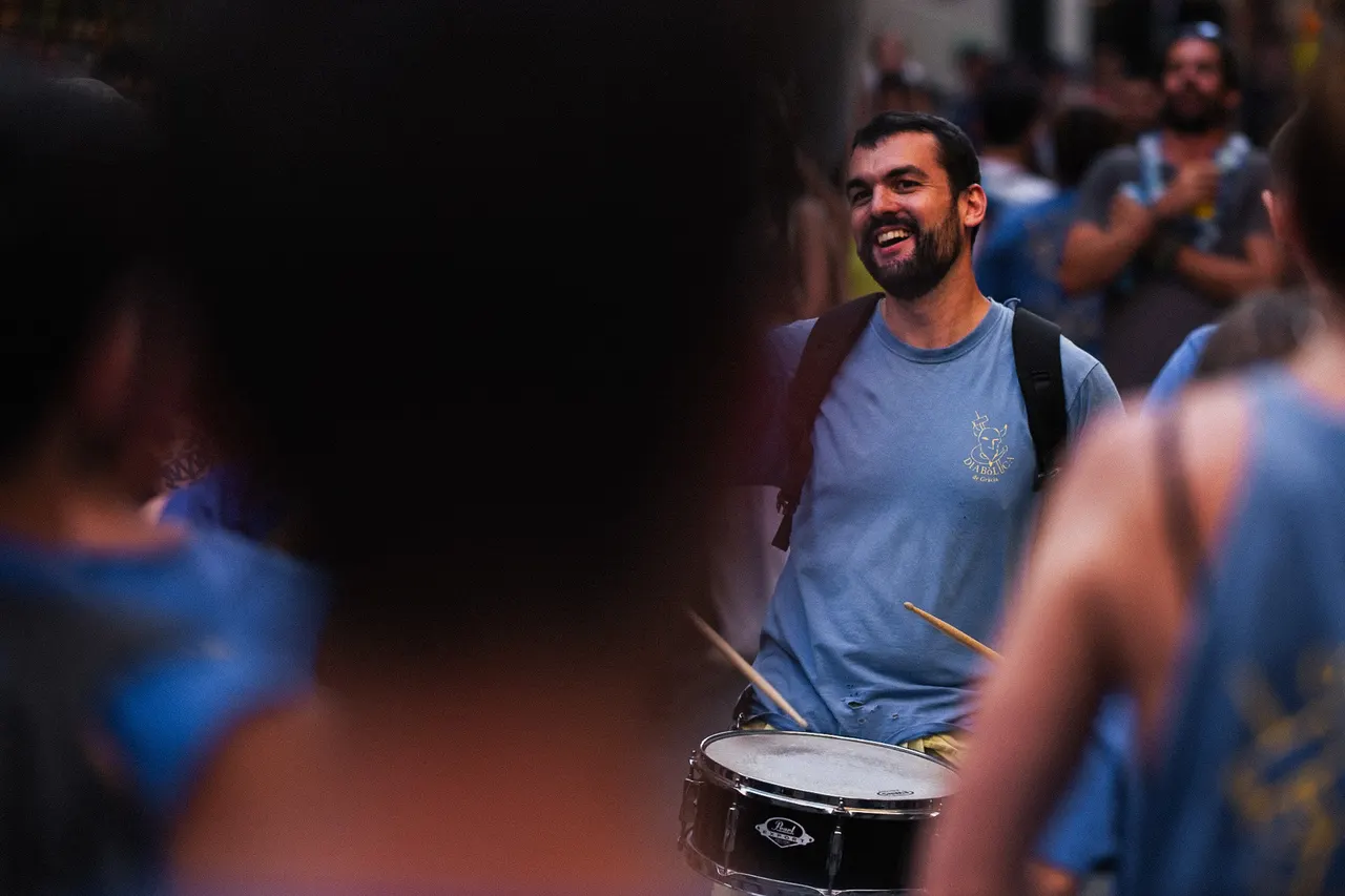 Batteur barbu qui sourit entre deux silhouettes floues