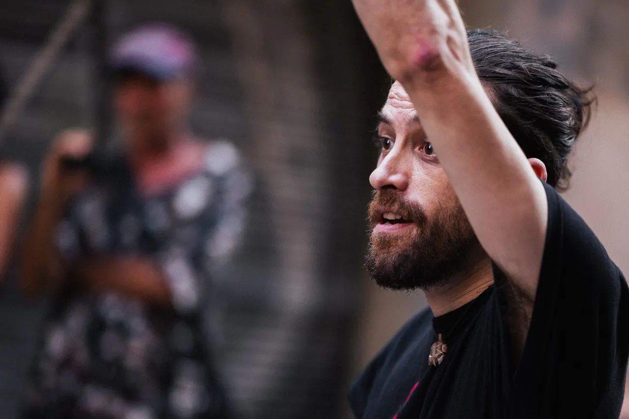 Musicien barbu, bras levé, regard vers le haut