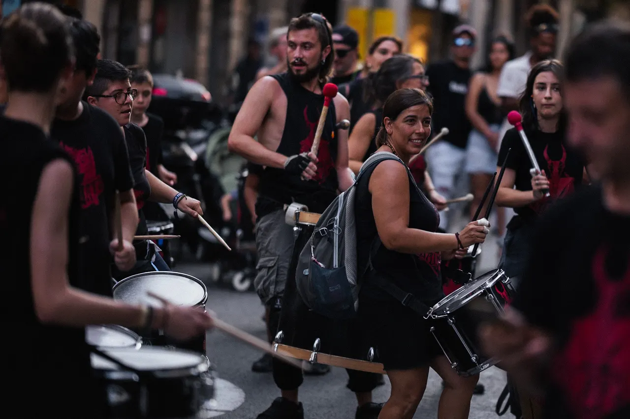 Percussionnistes en noir qui avancent en frappant