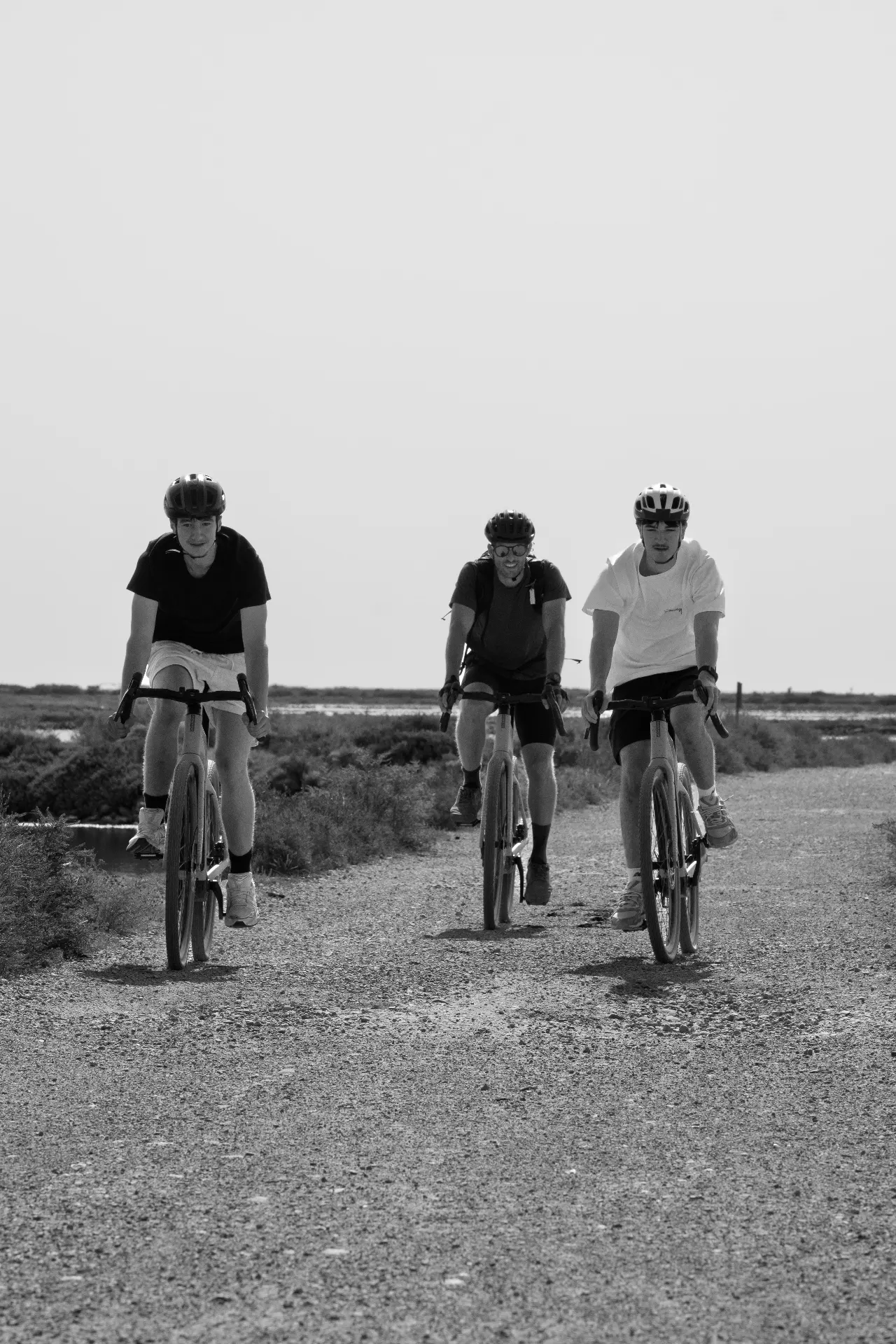 Trois cyclistes s'éloignant sur le sentier de gravier, Gruissan