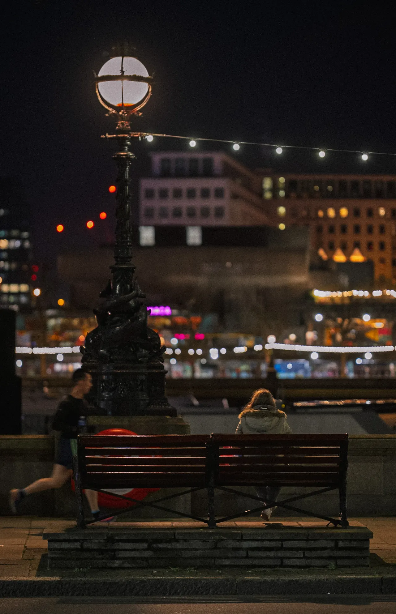 A bench and lamppost by the river at night