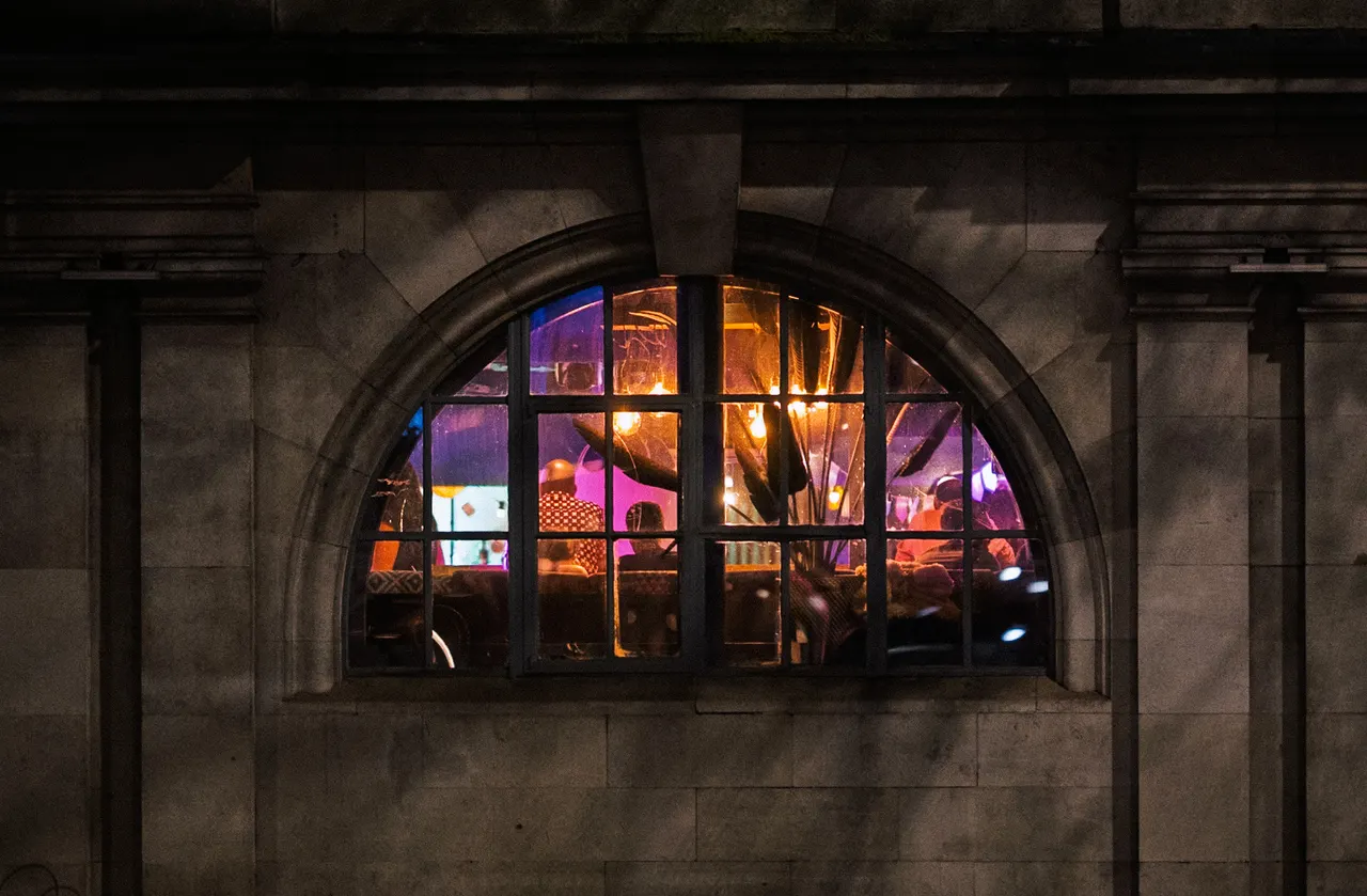 A lit half-moon window in a stone wall