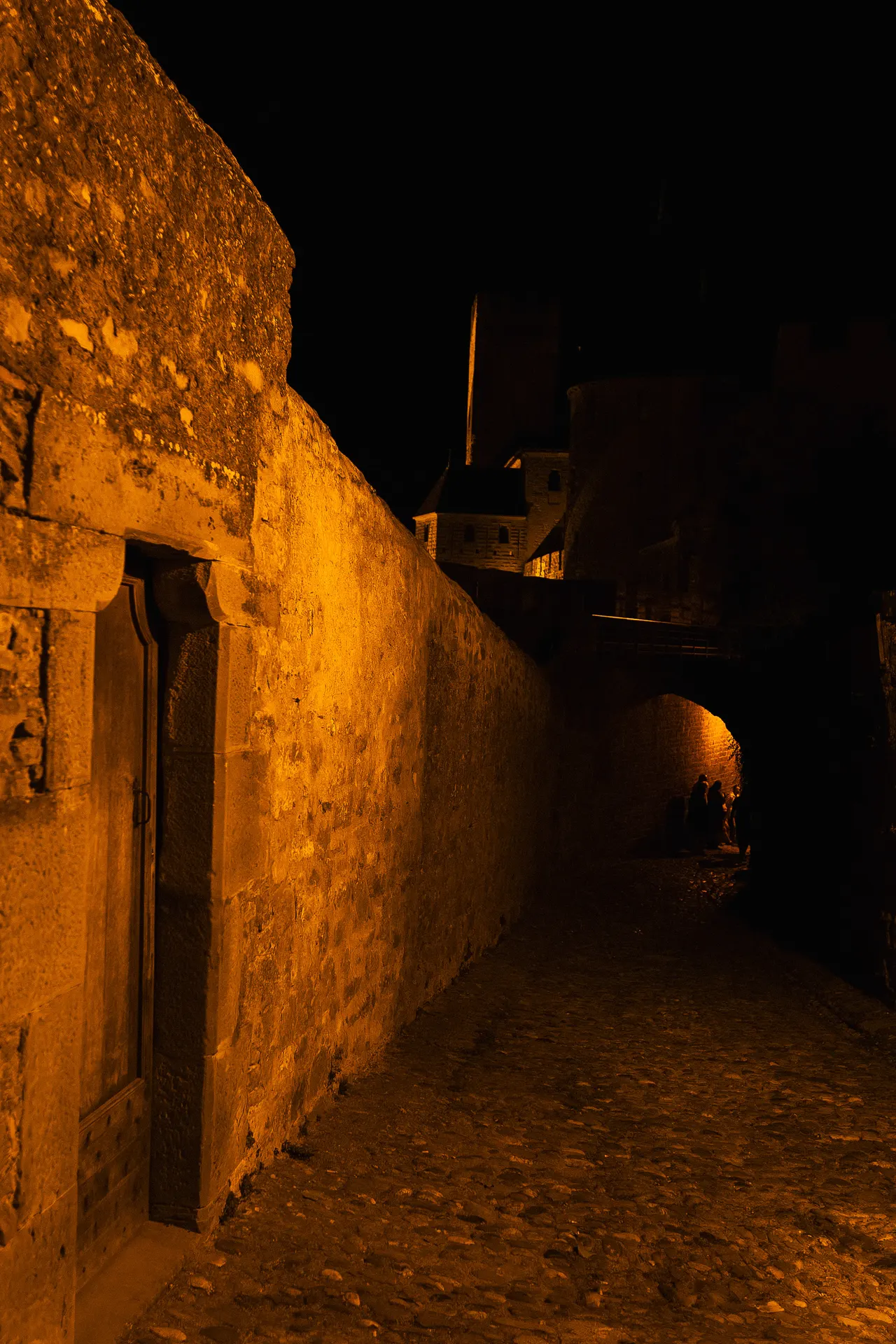 Rempart éclairé et ruelle pavée, la nuit