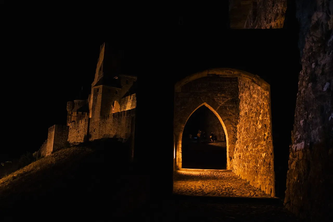 Porte en ogive éclairée dans les remparts, la nuit