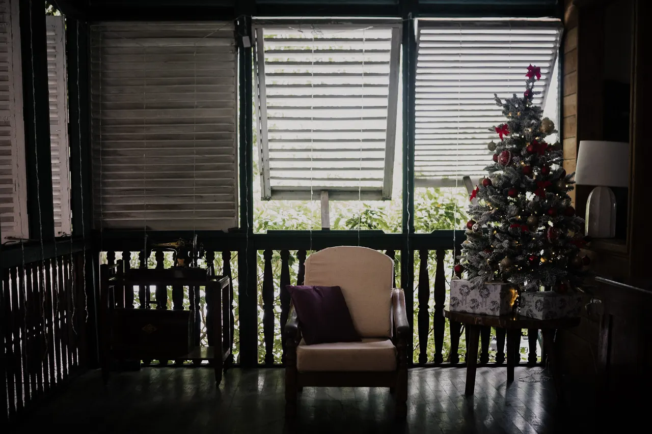 A shuttered veranda, armchair and Christmas tree